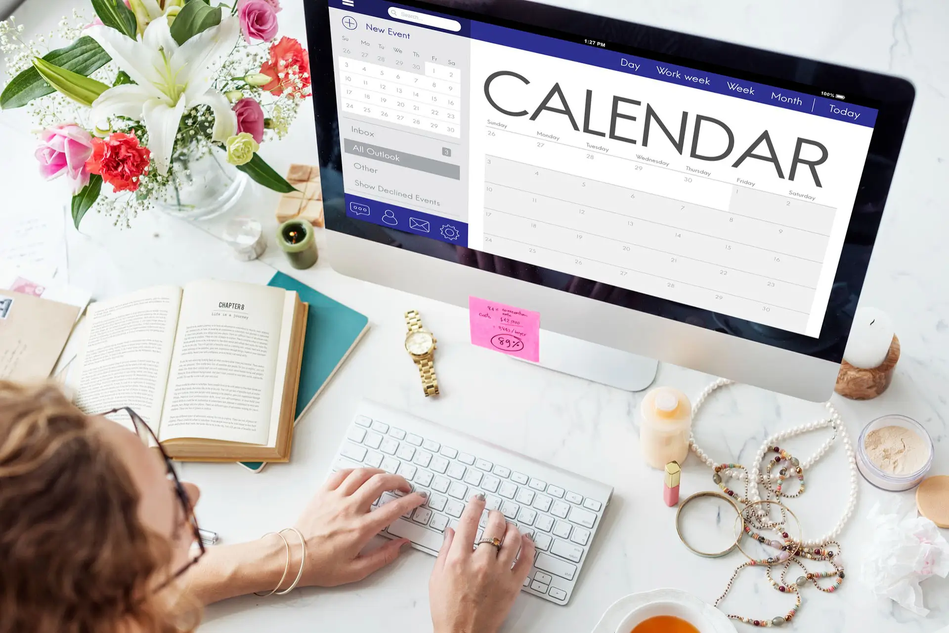 Someone creating a calendar on their computer with a busy desk