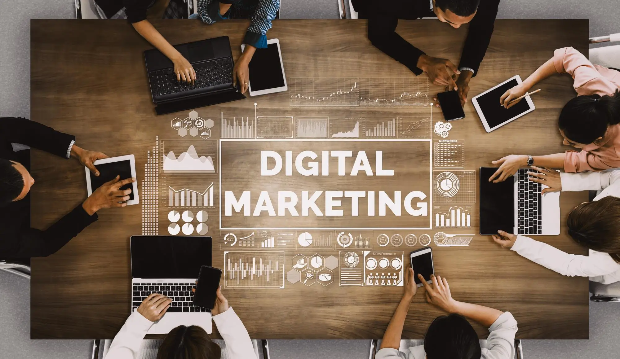 A group of people sat around a wooden table on multiple devices with the wording "Digital Marketing" in the middle of the table