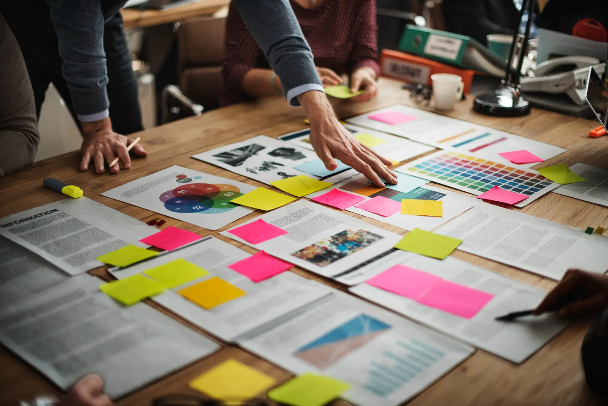 A crowded table full of paper and post-it notes being organised
